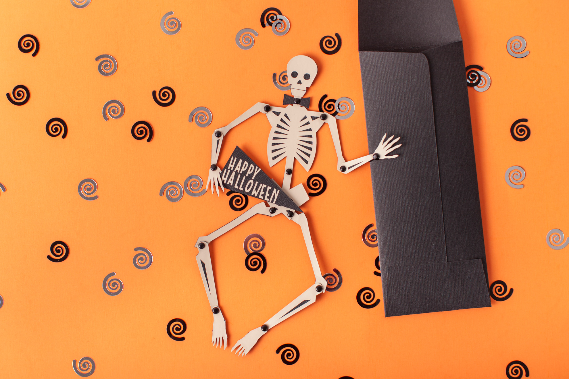 Paper skeleton and decorations on an orange background
