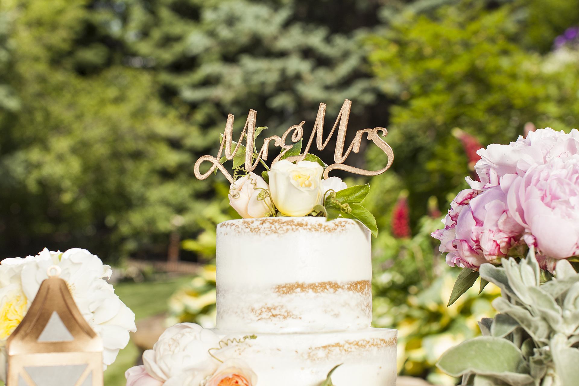 Wooden cake topper that says Mr. and Mrs. on a cake with flowers