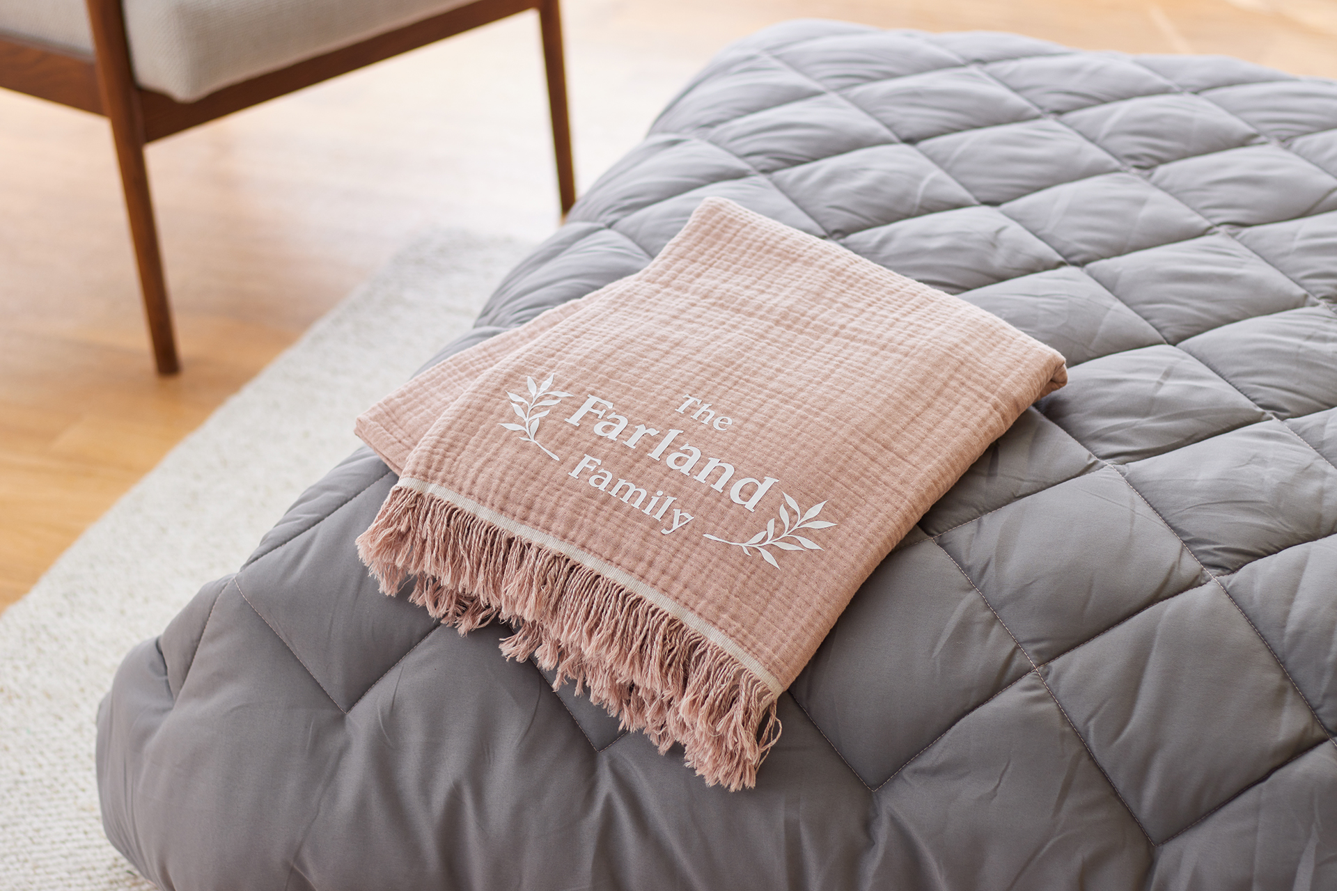Brown blanket with the words "The Farland Family" on a corner of a bed