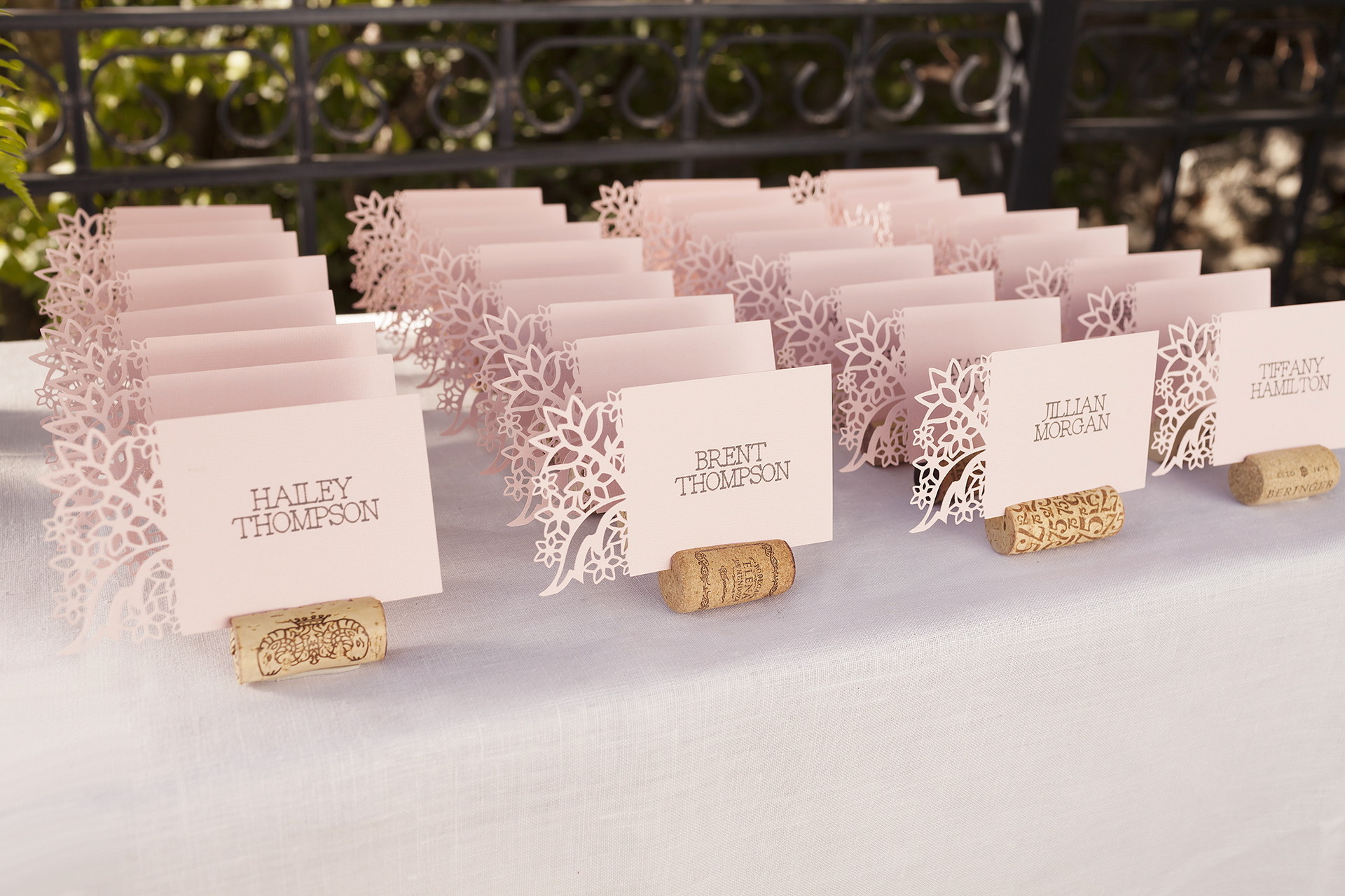 Name cards with a floral cutout on one side in rows on a table