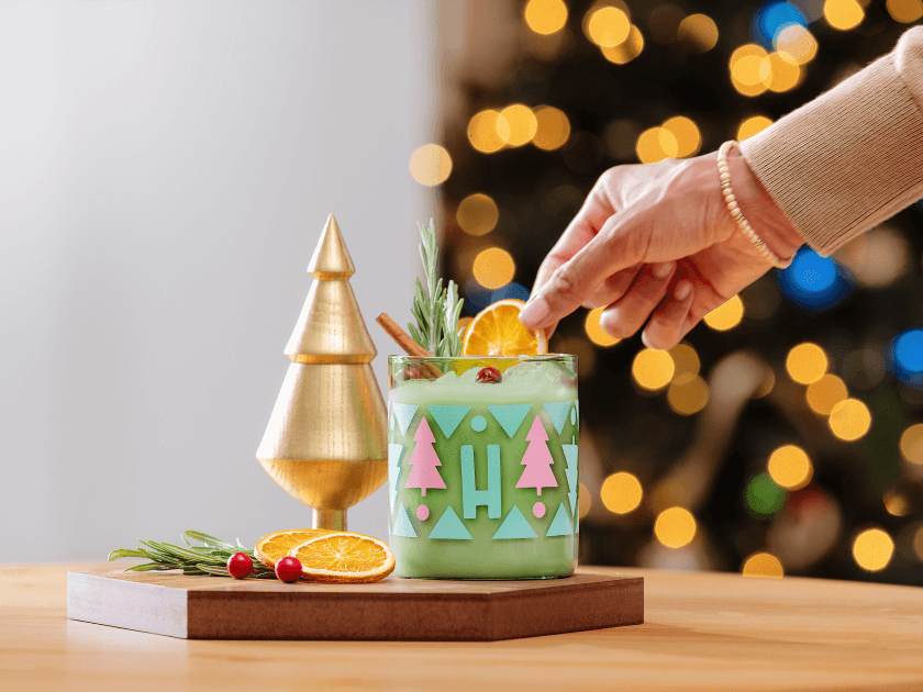Hand adding citrus garnish to personalised holiday tumbler glass
