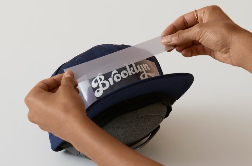 An iron-on design being taped to a hat.