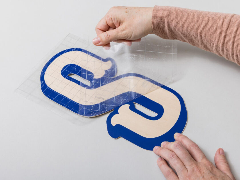 Woman's hand holding a smart phone with a personalized project template pulled up using Cricut's Design Space app