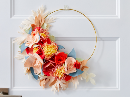 Paper flower wreath on a gold hoop hanging on a white door