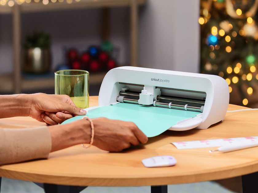 Woman's hands feeding material into Cricut Joy Xtra